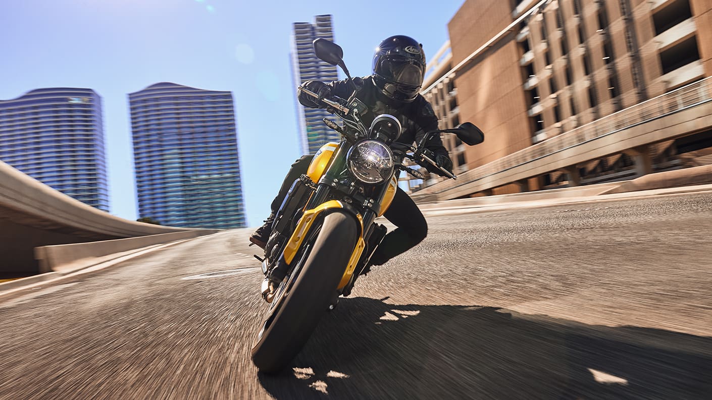 Triumph Trident 660 in cosmic yellow and sapphire black riding fast in urban setting