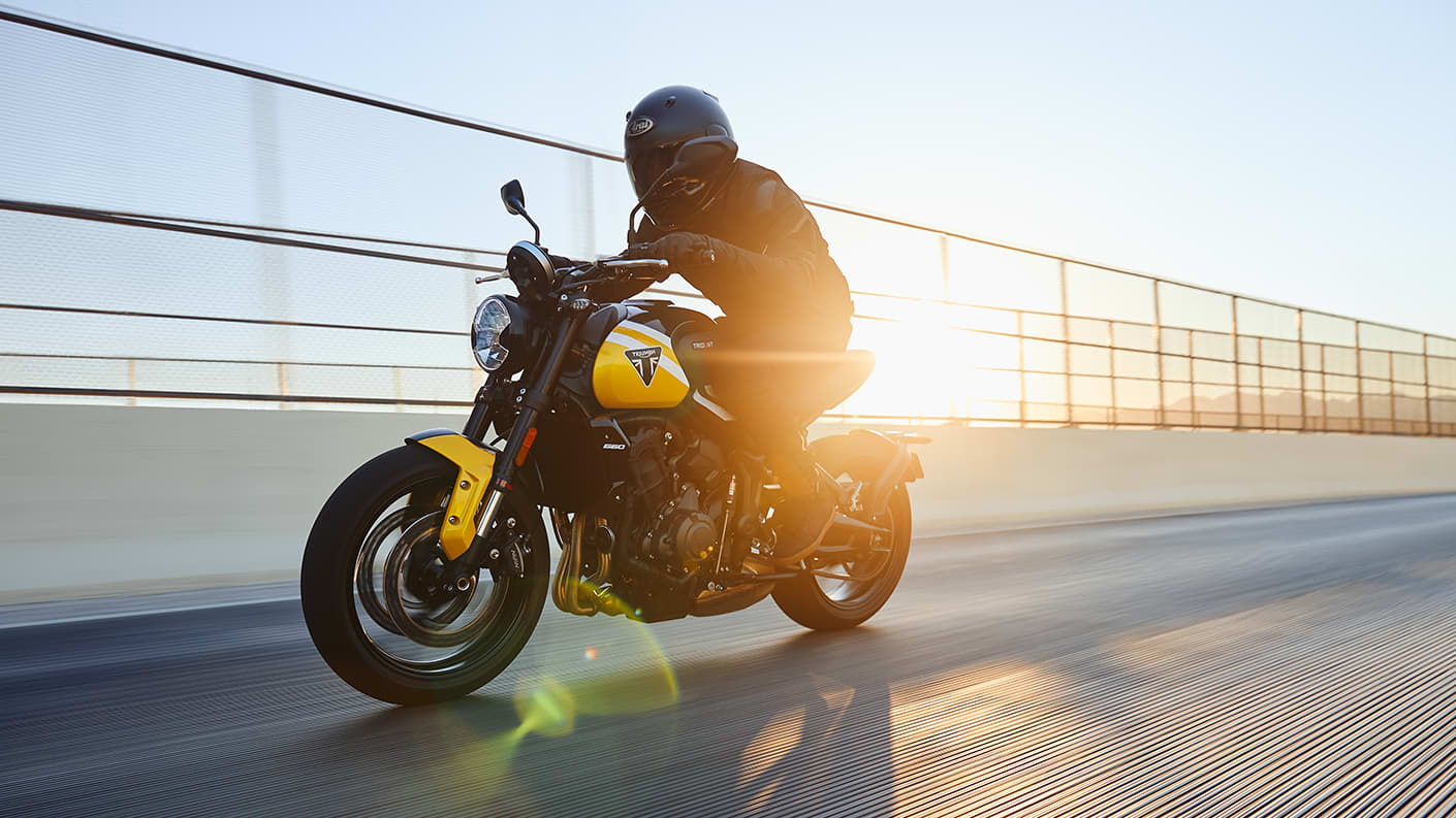 Triumph Trident 660 with rider on a bridge at sunset