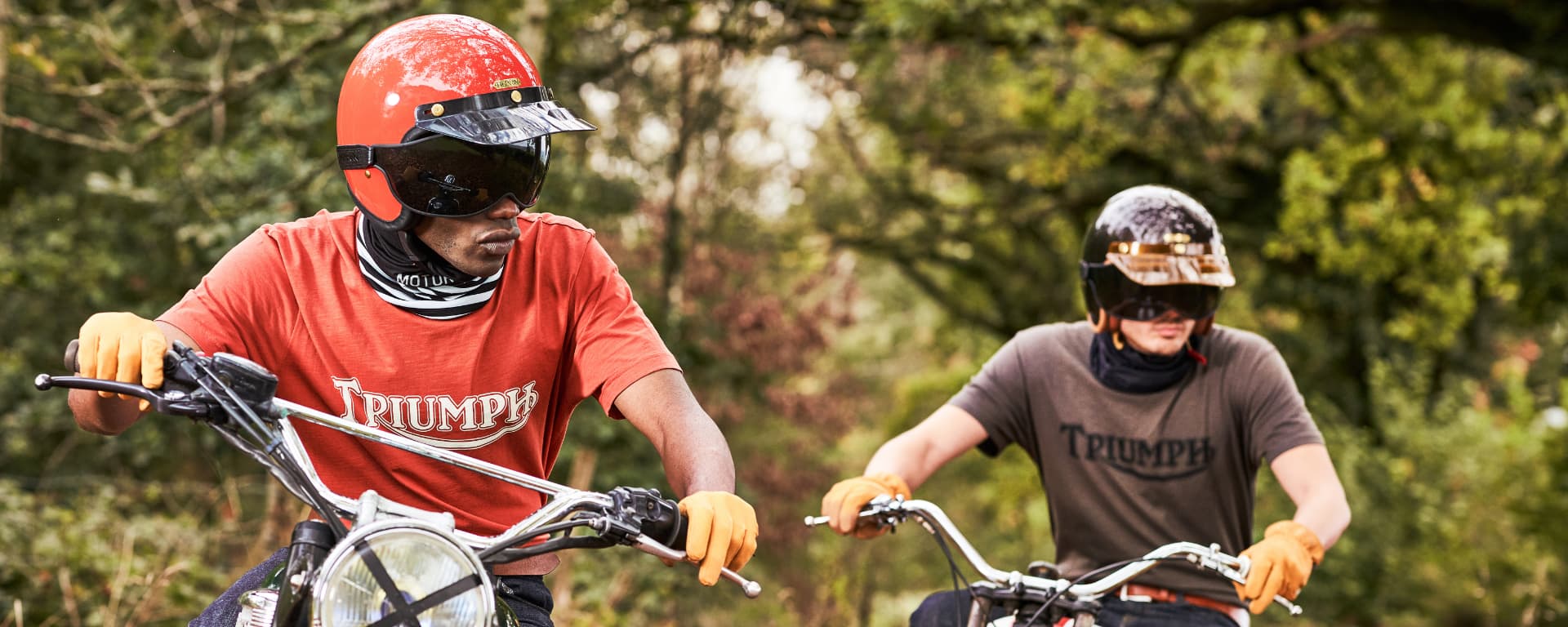 Two Triumph Clothing models are pictured wearing the Fork Seal tee while sat on two Triumph Motorcycles.)