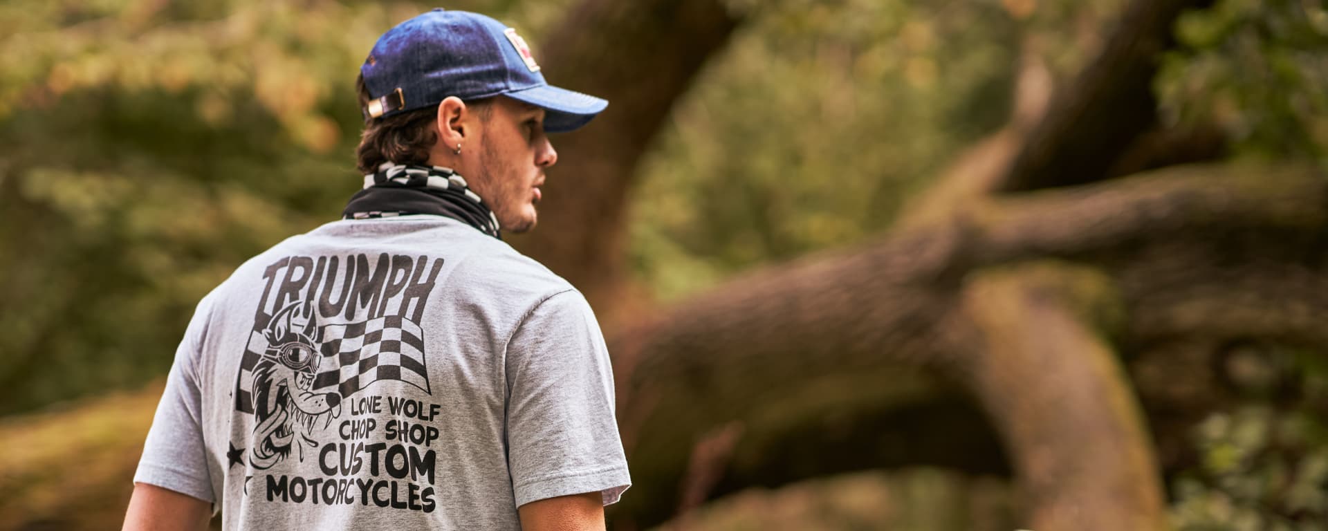 Triumph model wearing a Lone Wolf Tee in front of a large tree)